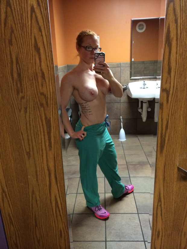 Hard body nurse showing off in the bathroom mirror