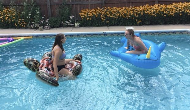 Two teens sitting on pool floats