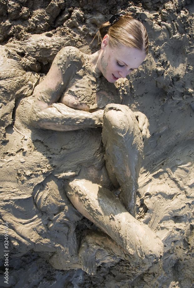 Naked woman playing in the mud, one nipple